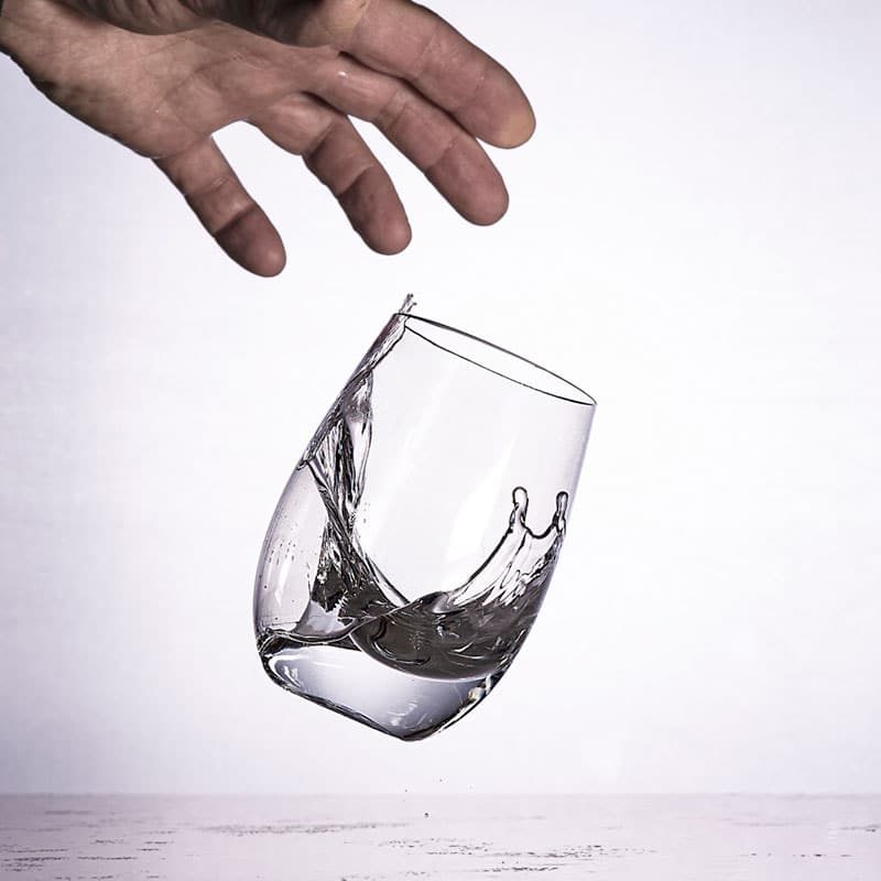 hand dropping clear glass with water